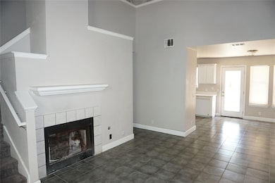 Unfurnished living room featuring a fireplace, dark tile patterned flooring, stairway, and a high ceiling