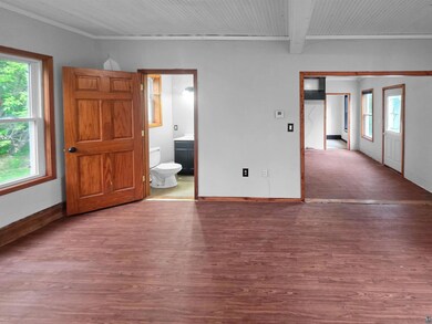 Spare room with wood finished floors, baseboards, beam ceiling, and ornamental molding