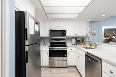 Kitchen featuring appliances with stainless steel finishes, open shelves, tasteful backsplash, white cabinetry, and light countertops