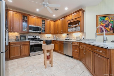 Kitchen featuring stainless steel appliances, brown cabinets, tasteful backsplash, and recessed lighting