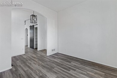 Spare room with arched walkways and dark wood-style floors