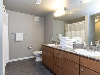 Bathroom featuring double vanity, dark tile patterned flooring, and a shower with curtain