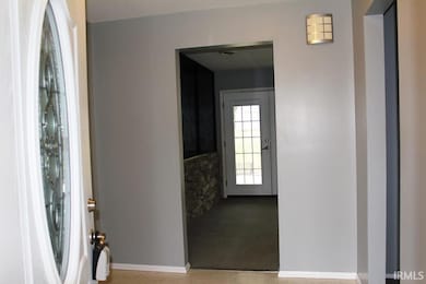 Carpeted foyer with baseboards