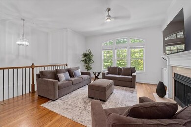 Living room featuring wood finished floors, a fireplace with flush hearth, a chandelier, and crown molding