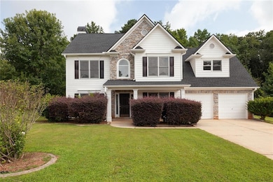 View of front facade featuring stone siding, concrete driveway, a front lawn, and a shingled roof