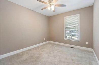Empty room with a ceiling fan and light carpet