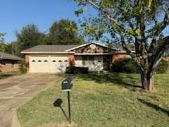 Single story home featuring a garage and a front lawn