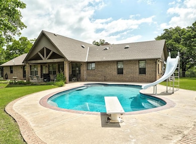 View of pool featuring a water slide, a patio, a diving board, and a lawn