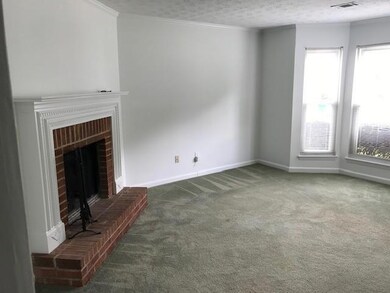 Unfurnished living room featuring ornamental molding, carpet floors, a brick fireplace, and a textured ceiling
