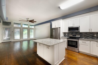 Kitchen with stainless steel appliances, ceiling fan, open floor plan, tasteful backsplash, and a kitchen island