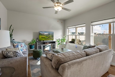 Living room featuring a glass covered fireplace, wood finished floors, and ceiling fan