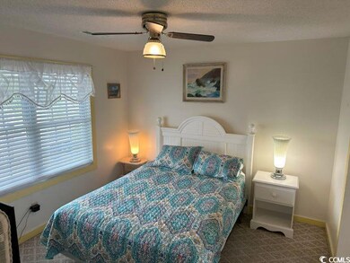 Carpeted bedroom with a textured ceiling and ceiling fan