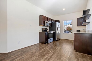 Kitchen with dark brown cabinetry, stainless steel appliances, and dark wood-style floors