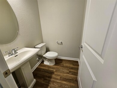 Half bathroom with a textured wall, a sink, toile