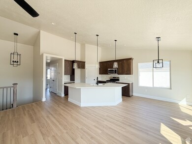 Kitchen featuring tasteful backsplash, decorative light fixtures, open floor plan, light wood-style flooring, and lofted ceiling