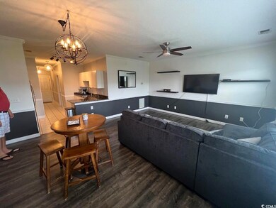 Living area featuring a ceiling fan, dark wood-style flooring, a textured ceiling, a chandelier, and crown molding