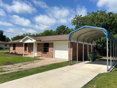 View of front of house with a front yard, a carport, and a garage