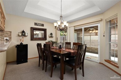 Carpeted dining space with a chandelier and a raised ceiling