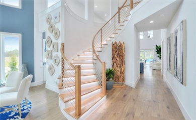Foyer featuring a towering ceiling, plenty of natural light, hardwood / wood-style floors, stairway, and recessed lighting