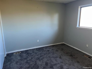 Carpeted spare room with a textured ceiling and baseboards