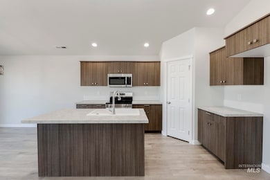 Kitchen with light countertops, appliances with stainless steel finishes, an island with sink, light wood-style flooring, and recessed lighting