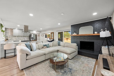 Living area with a brick fireplace, recessed lighting, and light wood-style flooring