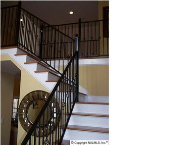 A VIEW OF THE STAIRCASE AND WROUGHT IRON RAILING.