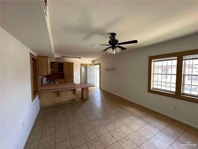 Kitchen featuring baseboards, a peninsula, a ceiling fan, range with electric stovetop, and a breakfast bar