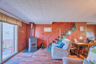Living area with plenty of natural light, stairway, wood finished floors, wood walls, and a wood stove