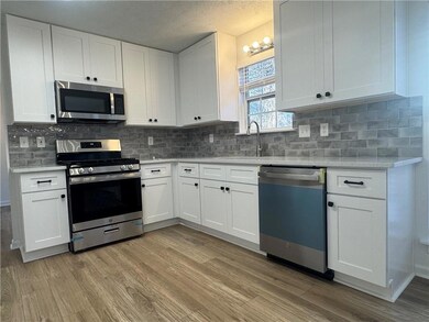 Kitchen with appliances with stainless steel finishes, white cabinets, backsplash, and a textured ceiling