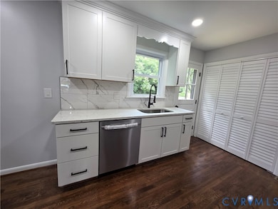 Kitchen with stainless steel dishwasher, tasteful backsplash, white cabinets, light stone countertops, and dark wood-type flooring