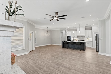 Living room featuring crown molding, a chandelier, light wood-style floors, ceiling fan, and recessed lighting