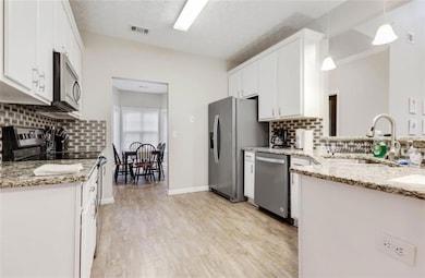 Kitchen featuring white cabinets, a sink, backspla