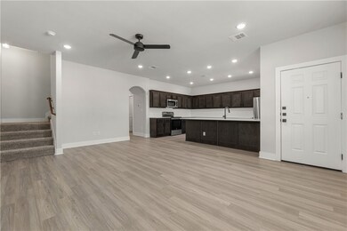 Unfurnished living room featuring ceiling fan, lig