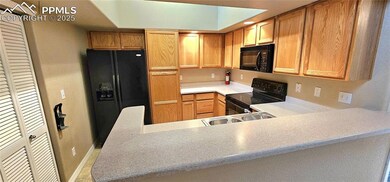 Kitchen with black appliances, a sink, light countertops, and a peninsula