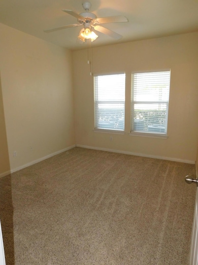 Carpeted spare room with baseboards and ceiling fan