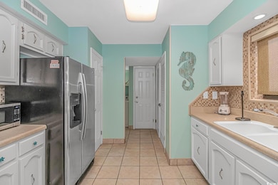 Kitchen with sink, white cabinetry, light tile pat