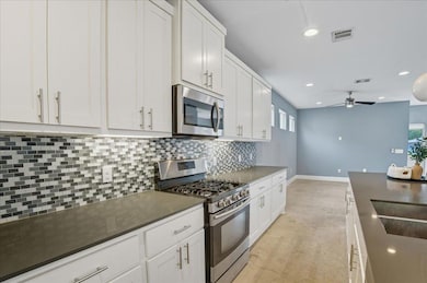Kitchen featuring appliances with stainless steel finishes, white cabinets, tasteful backsplash, recessed lighting, and a ceiling fan