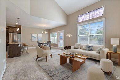 Living room featuring light tile patterned floors, high vaulted ceiling, a chandelier, and light carpet