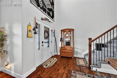 Foyer featuring dark wood-type flooring, stairs, and a high ceiling