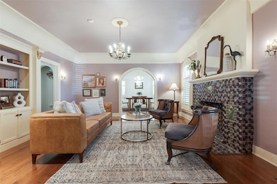 Living area with a chandelier, light wood-type flooring, arched walkways, and a fireplace