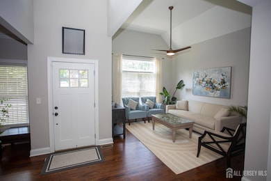 Welcoming entryway with soaring ceilings, a modern ceiling fan, and rich dark wood-style flooring that adds warmth and elegance.