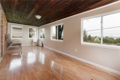 Spare room featuring brick wall, ornamental molding, light wood-type flooring, and wood ceiling