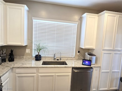 Kitchen featuring a sink, dishwasher, white cabine