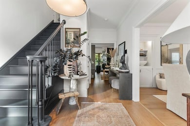 Entryway with ornamental molding, light wood-style floors, and stairs