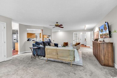 Living room featuring light carpet, french doors, ceiling fan, baseboards, and a textured ceiling