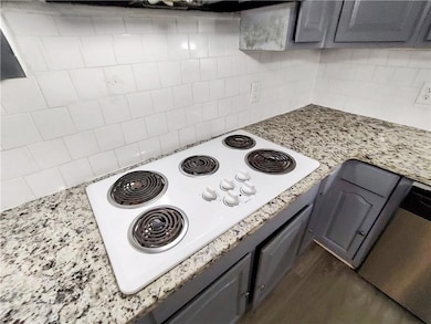 Kitchen view of white electric stovetop, gray cabinetry, and tasteful backsplash