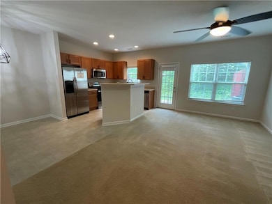 Kitchen with open floor plan, baseboards, ceiling fan, and light countertops