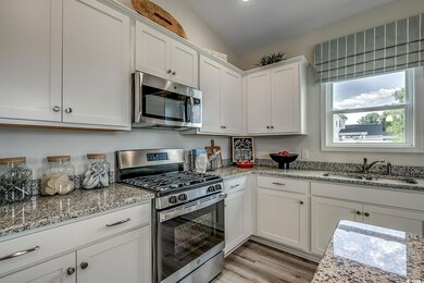 Kitchen featuring white cabinets, light stone coun