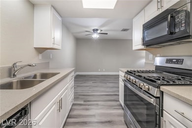 Kitchen featuring appliances with stainless steel finishes, white cabinetry, light stone counters, and light wood-style floors